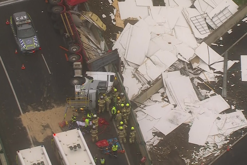 A rolled over truck surrounded by multiple emergency workers.