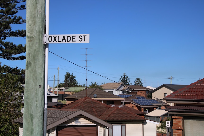 Oxlade Street sign and homes in background, clear blue sky.