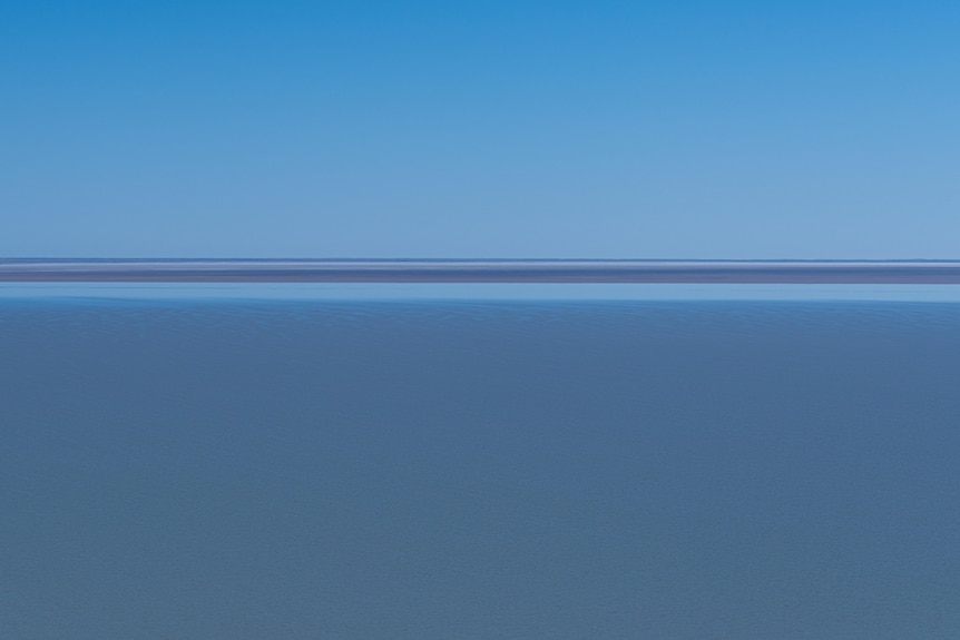 Aerial looking across at a horizon, with blue water taking up most of the screen