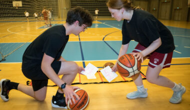 To children dribbling a basketball each while picking up notes with fractions written on them