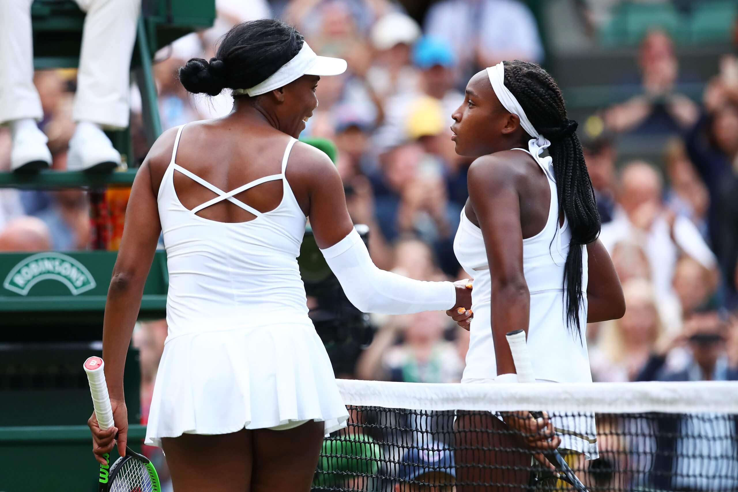 Venus Williams (left) shakes hands with Coco Gauff (right) over the net.