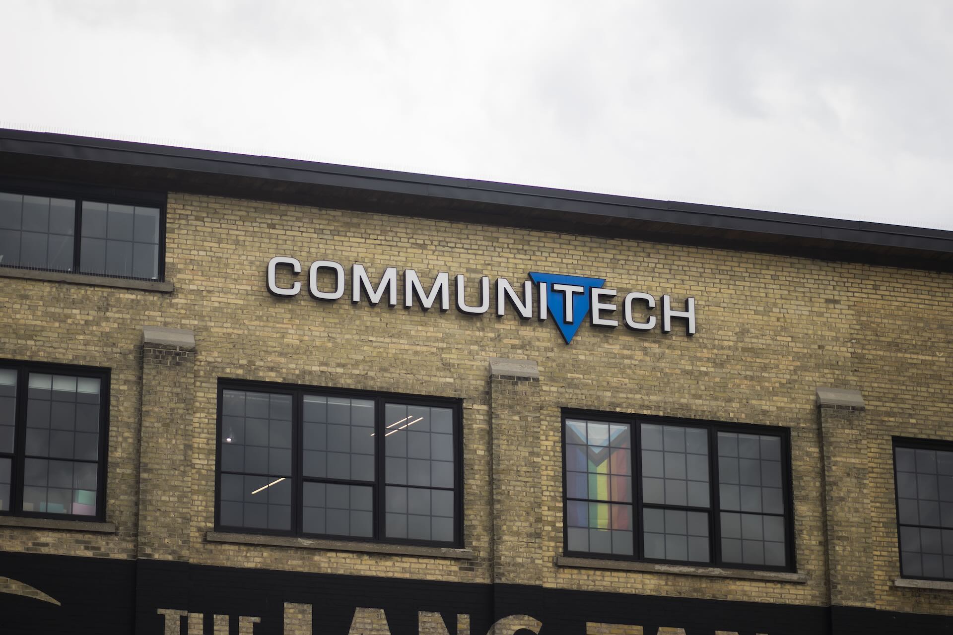 An image of the exterior of a brick building against a grey sky. The building signage says Communitech, with a blue triangle logo.