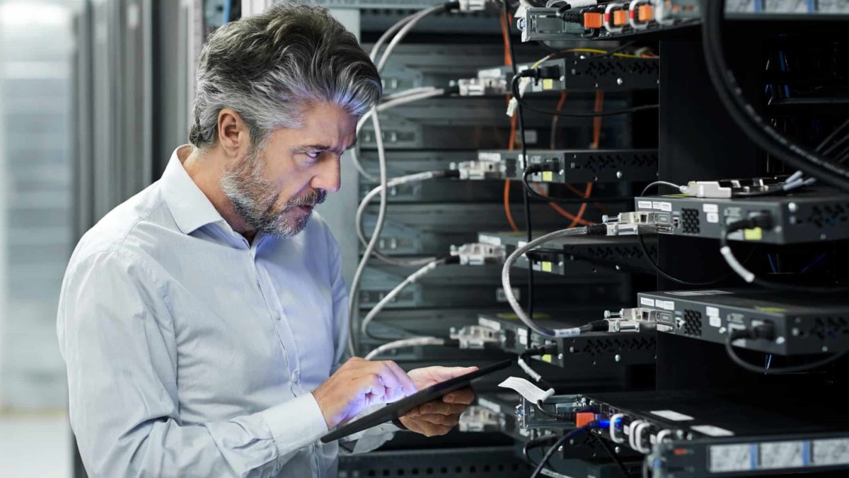 Man on a tablet in a room with data centre technology.