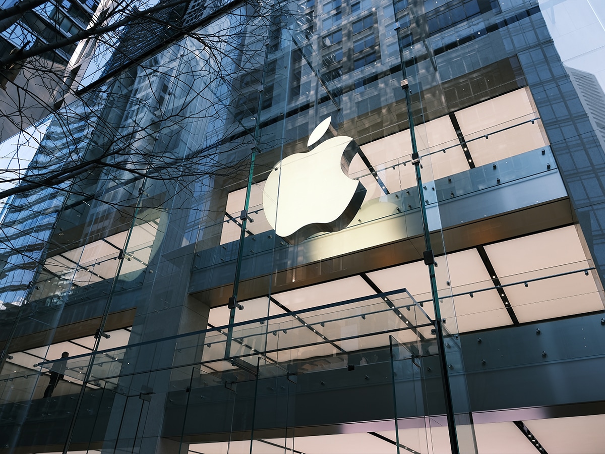 Apple Store Sydney exterior with large illuminated Apple logo on glass facade, reflecting city buildings.