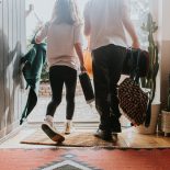 Two young children wearing school uniforms exit their front door - stock photo