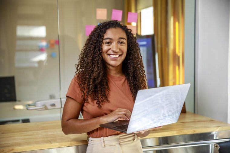 Portrait of happy businesswoman holding laptop at office - stock photo