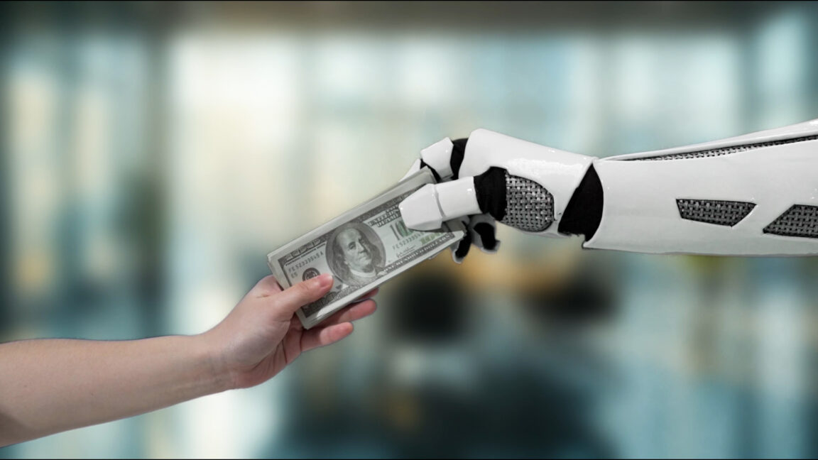 A robotic hand exchanges dollar bills with a human hand,
