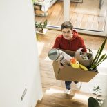 Woman carrying box while moving and cleaning up at home happily - stock photo