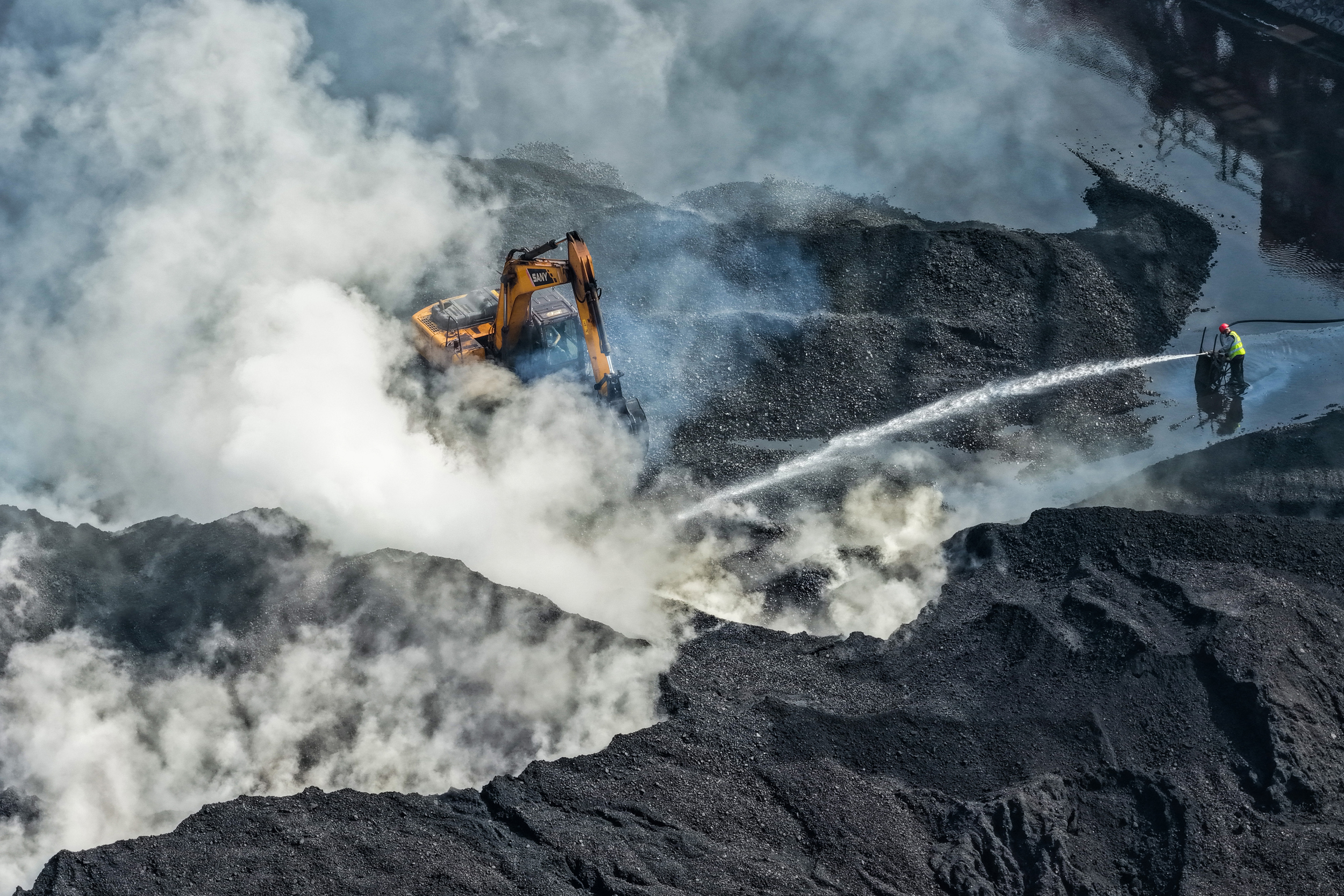 A worker sprays water on coal at a storage yard in Nanjing, China, on Oct. 31, 2025. Credit: CFOTO/Future Publishing via Getty Images