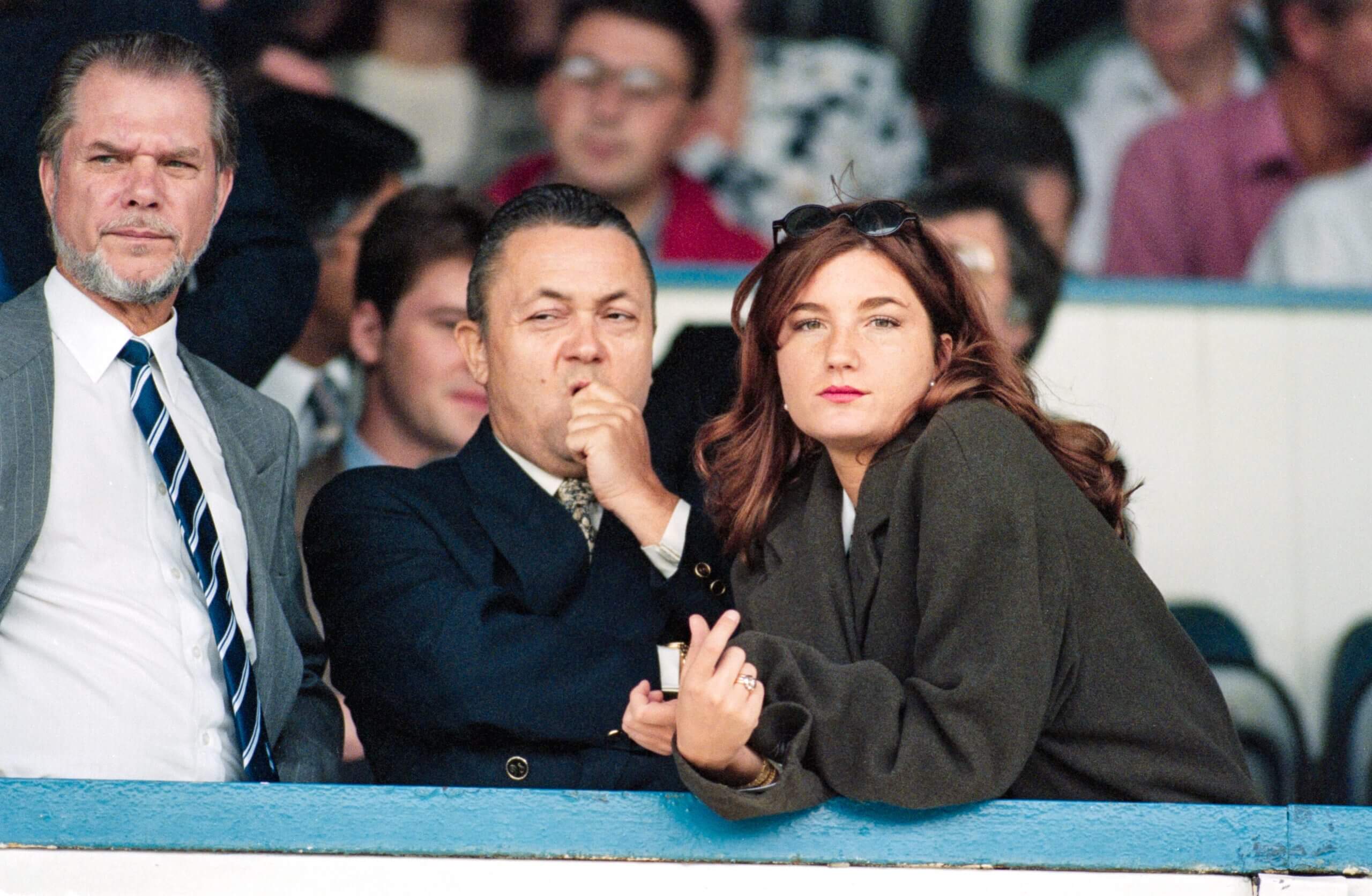 Two men and a woman are pictured watching a football match