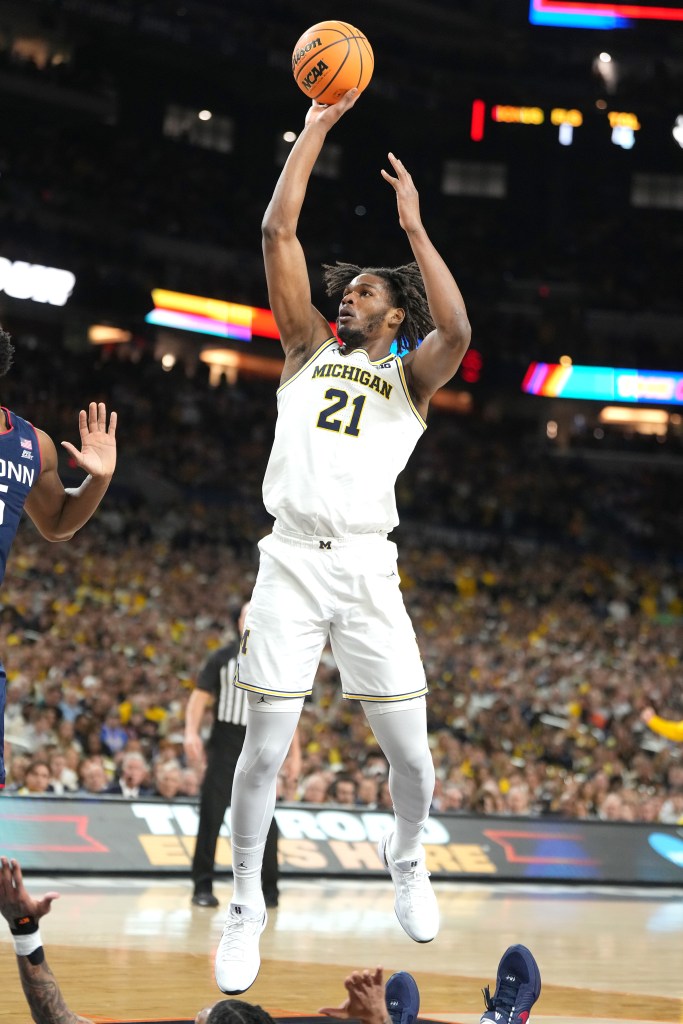 Michigan player Dug McDaniel (21) in mid-air shooting a basketball.