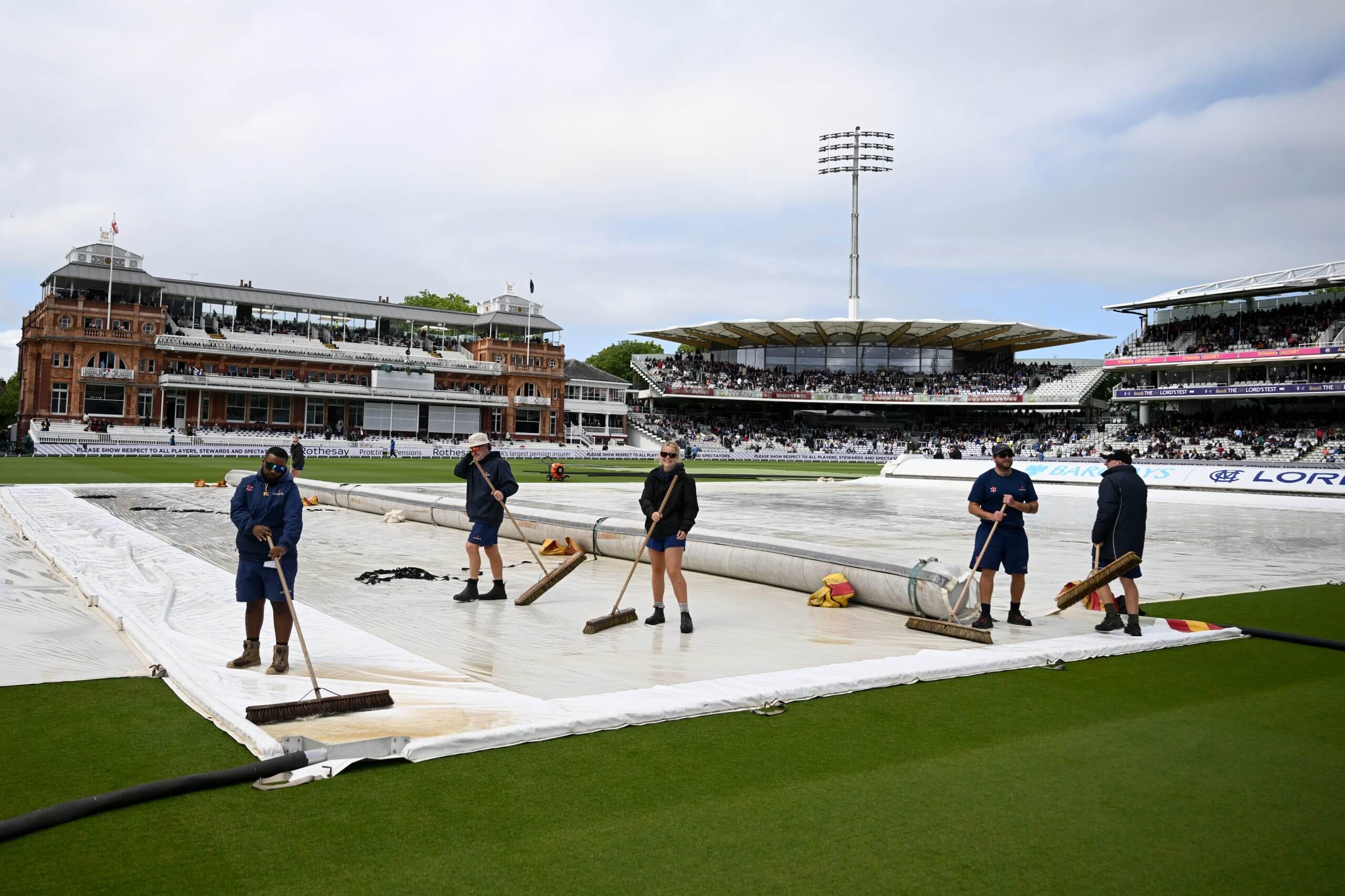 Ground staff mop up the water on the covers