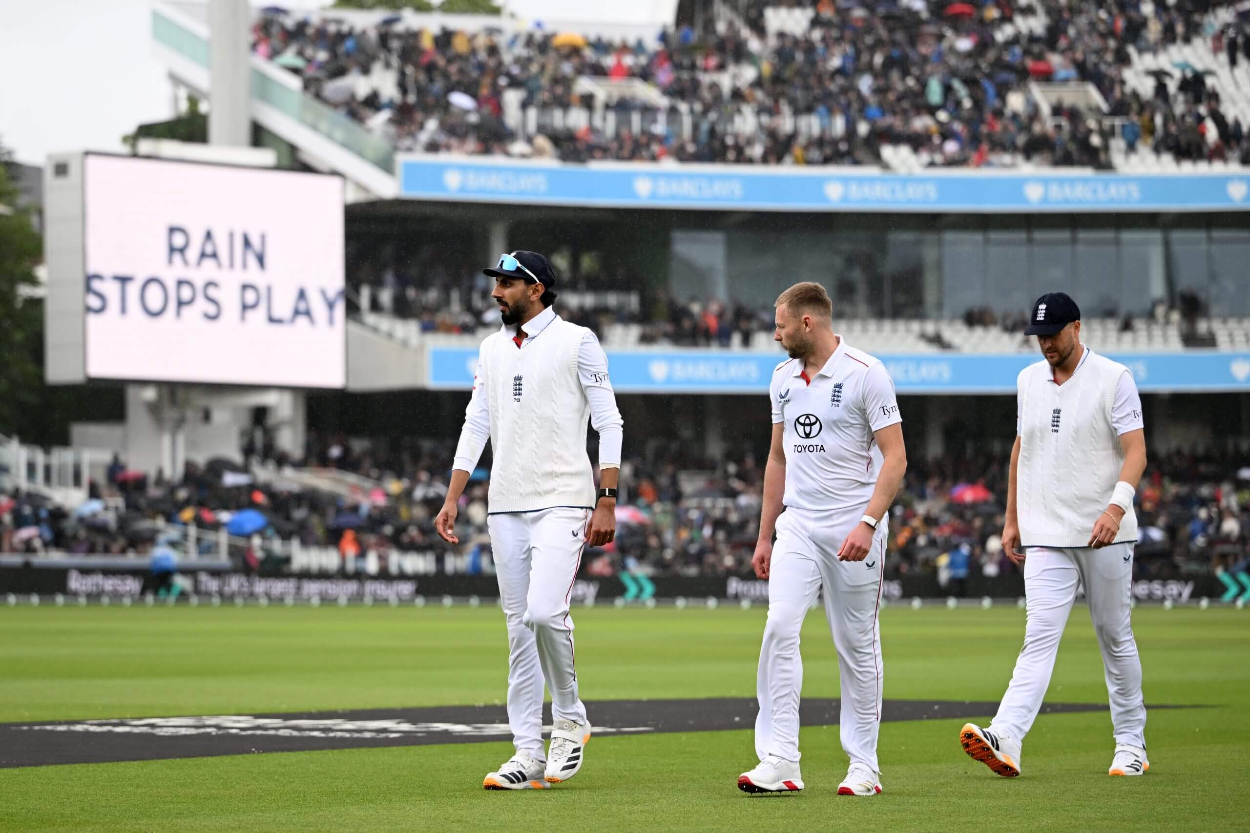 Shoaib Bashir, Gus Atkinson and Ollie Robinson leave the field as rain stops play at Lord's
