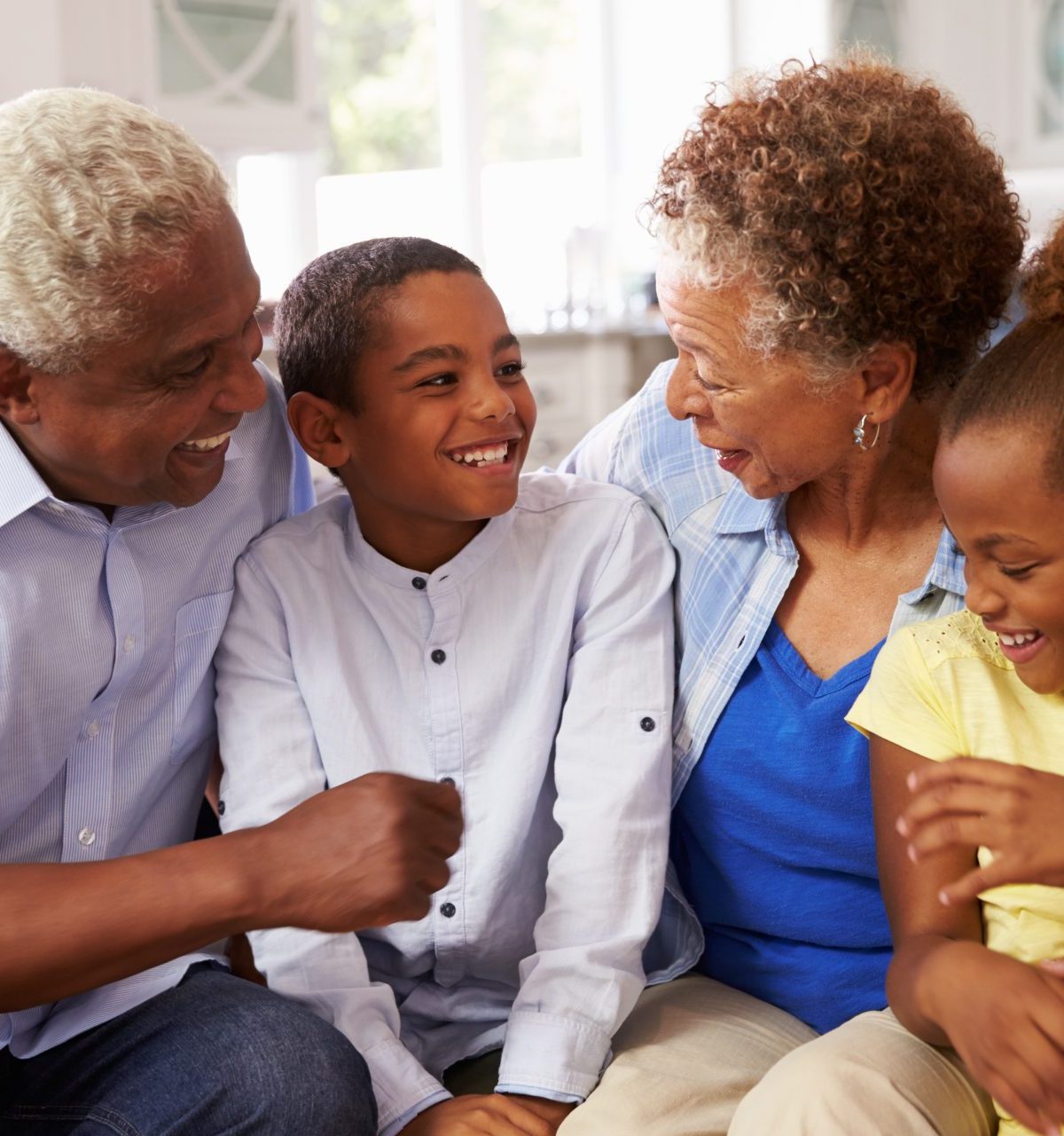 Grandparents and their young grandchildren relaxing at home - stock photo