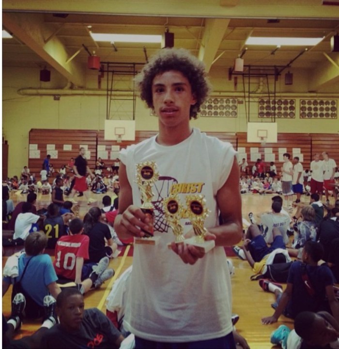 A teenage Jose Alvarado holds trophies during a basketball camp at Christ the King Regional High School
