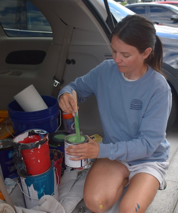 Kailey Rorer, a Sycamore artist, carefully stirs green paint Thursday in the back of her SUV for the mural she's painting on a wall at Block 59 in Naperville. (Steve Metsch/Naperville Sun)