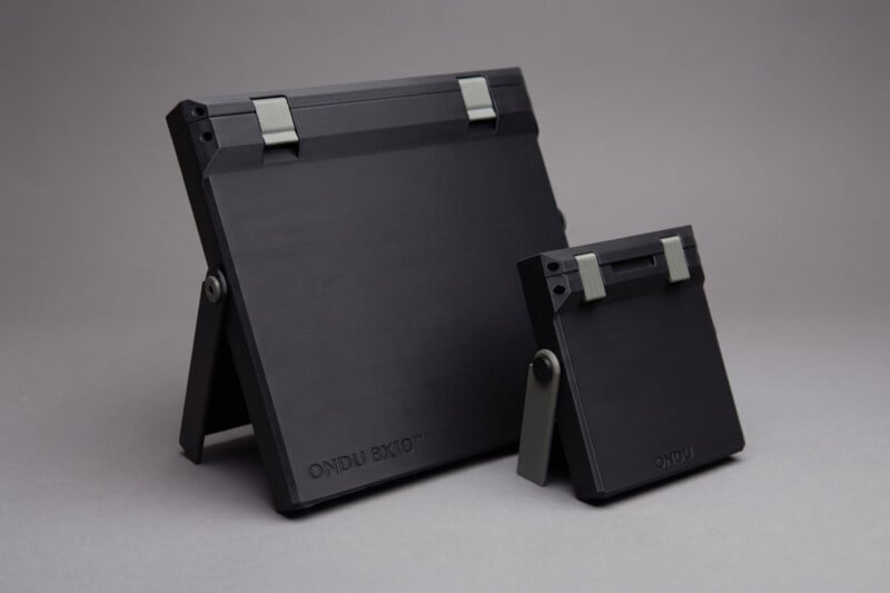 Two sleek, black, rectangular camera devices of different sizes stand side by side on a gray background, each with folding supports and metallic hinges. The larger device is labeled "ONDU 8x10".