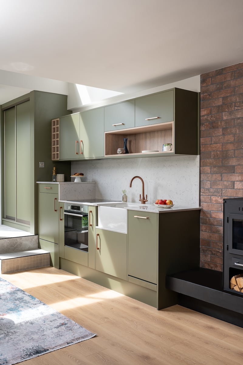 A new warm-green kitchen was installed to maximise storage, featuring an attractive splashback and worktop