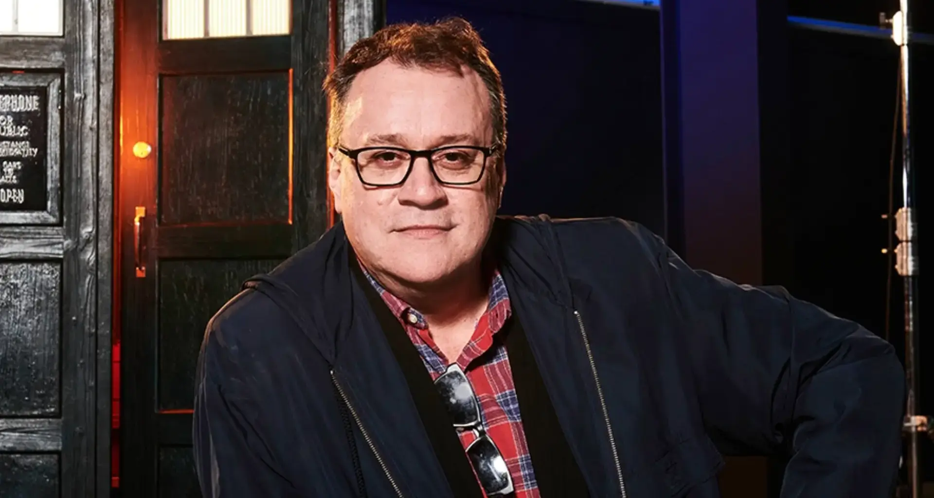 Russell T Davies poses in front of a Tardis