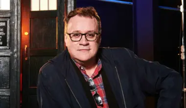 Russell T Davies poses in front of a Tardis