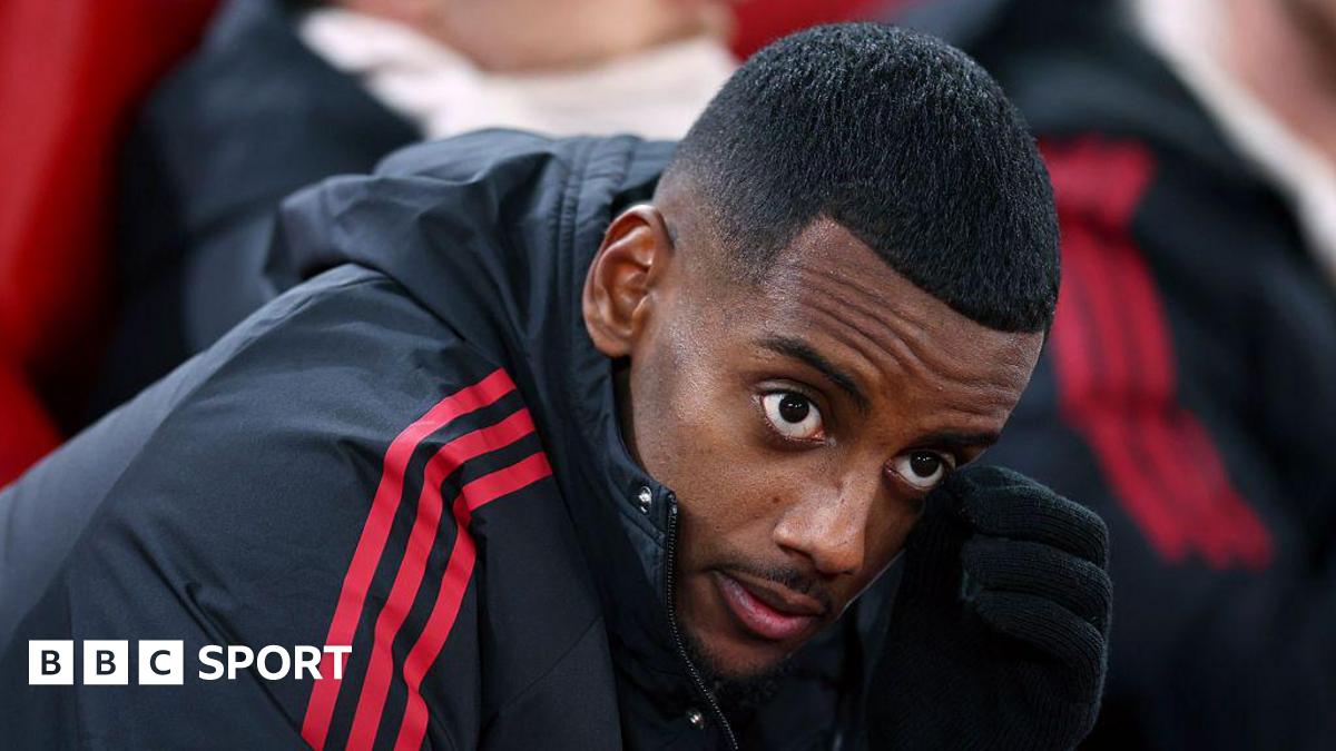 Alexander Isak looks on from the bench in a zip-up dark jacket with red stripes before the Champions League game between Liverpool and PSV Eindhoven at Anfield on 26 November, 2025