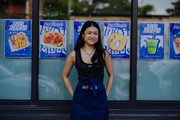 Ina's Bagels owner Salina Tam outside her venue with posters she designed herself.