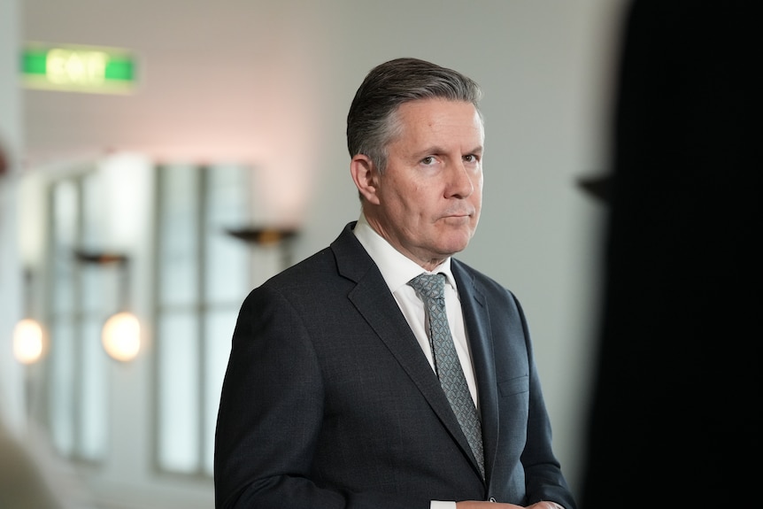 A man in a suit and tie looks sternly ahead.