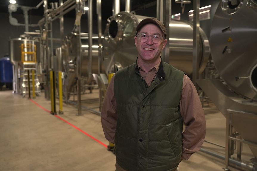 A man standing in front of distilling machinery.