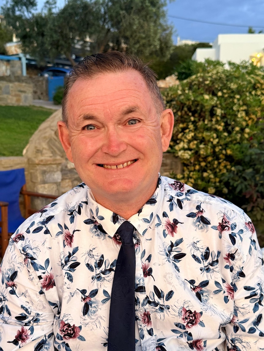A smiling older man in a patterned tie and shirt.
