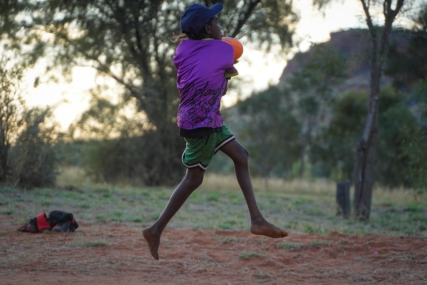A child takes a mark during a game of Aussie Rules football.