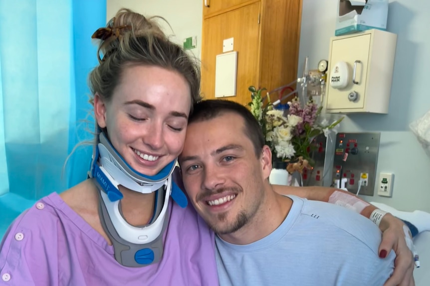 Lucy Scott wearing a neck brace in hospital with her partner Jethro Tessan.