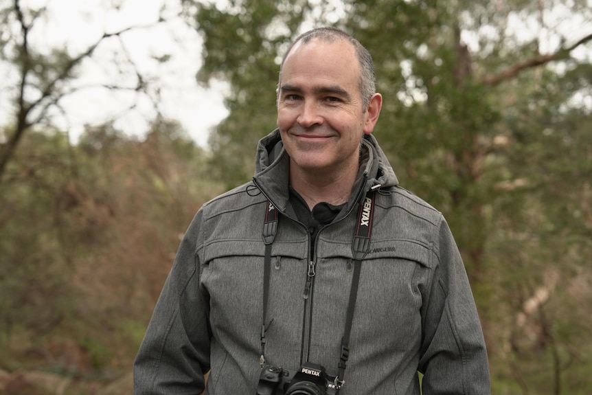 A man wearing a grey jacket looking into the camera.