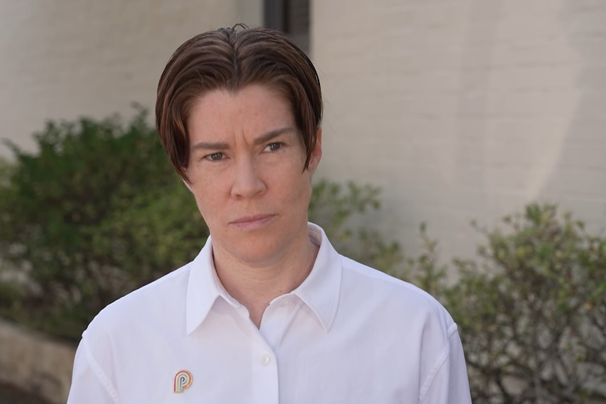 A person with a short hair cut in a button white shirt.