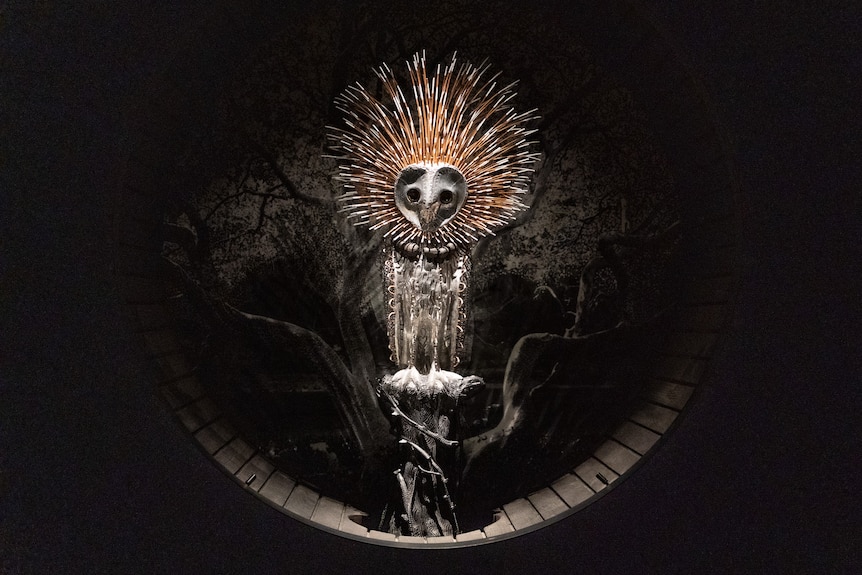 An artwork showing a lit-up owl, perched in a tree. It is surrounded by darkness.