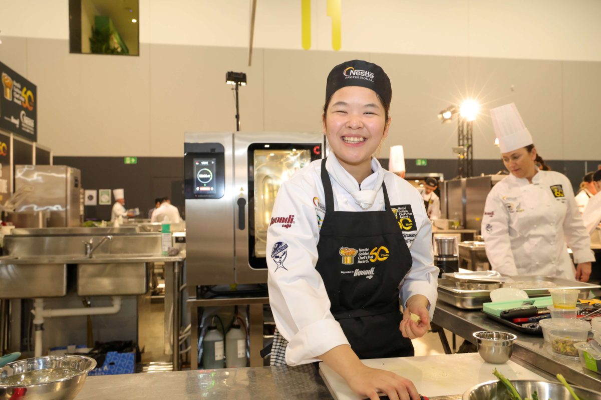 Chef in the kitchen smiles at the camera.