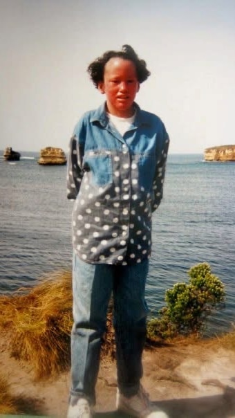 Carly stands in front of the ocean, wearing a denim outfit. 