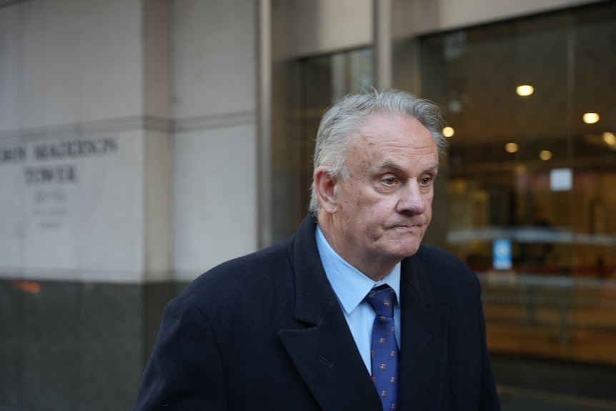 Mark Latham outside court in a suit, with microphones in his face.
