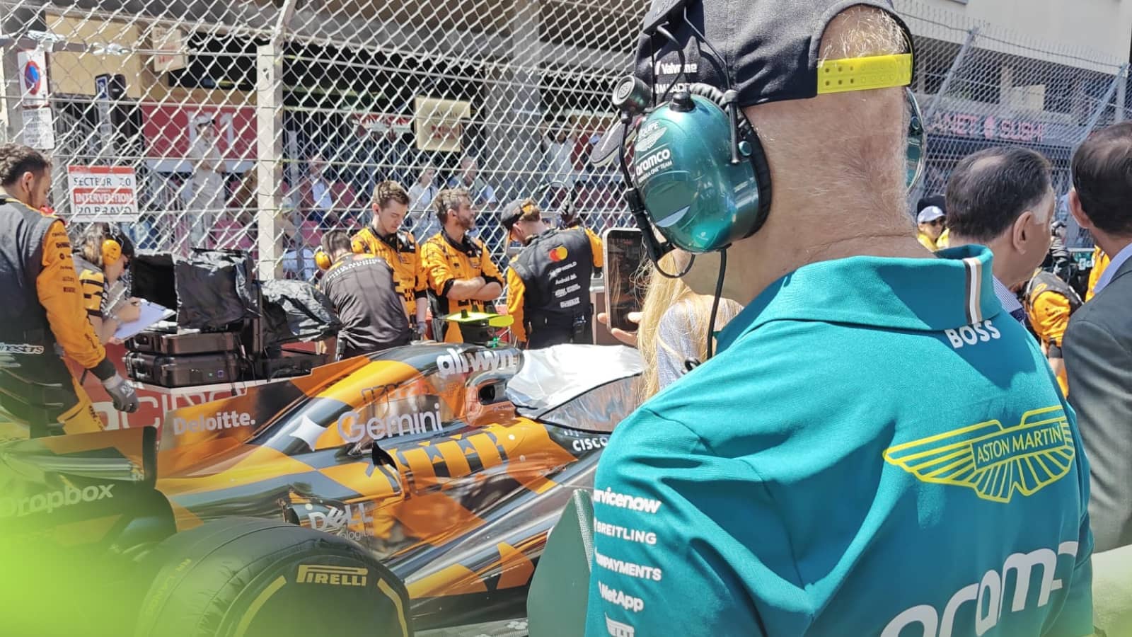 An over-the-shoulder shot of Adrian Newey examining Lando Norris's McLaren MCL40 on the grid in Monaco