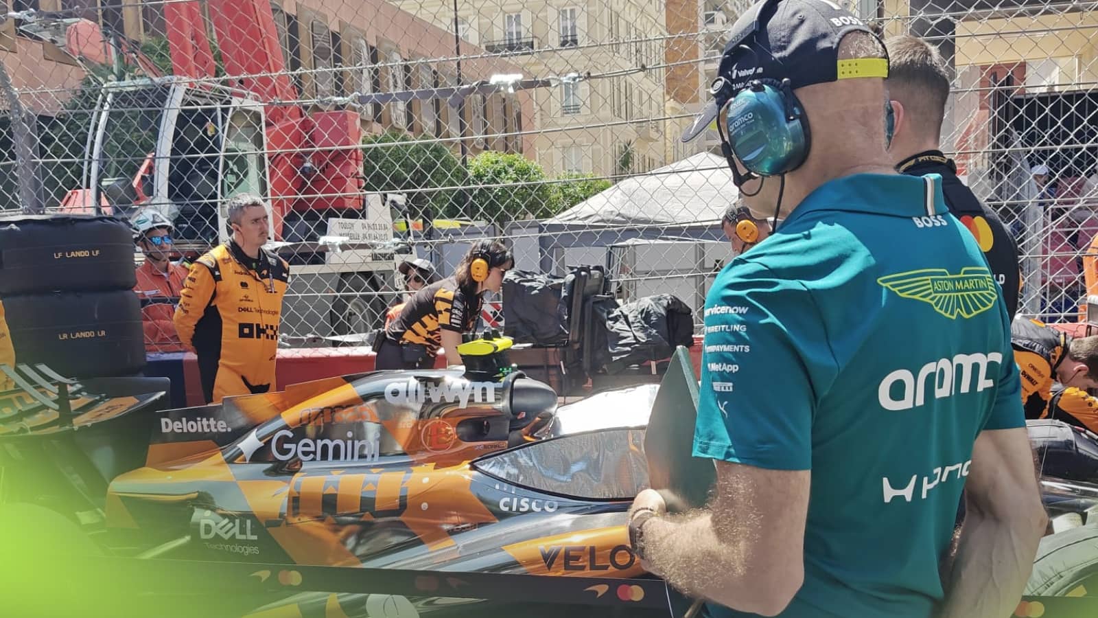 A behind shot of Adrian Newey studying Lando Norris's McLaren MCL40 on the grid in Monaco