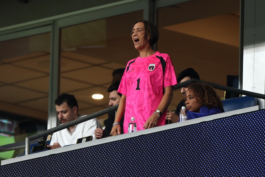 A woman stands up in the crowd at a stadium