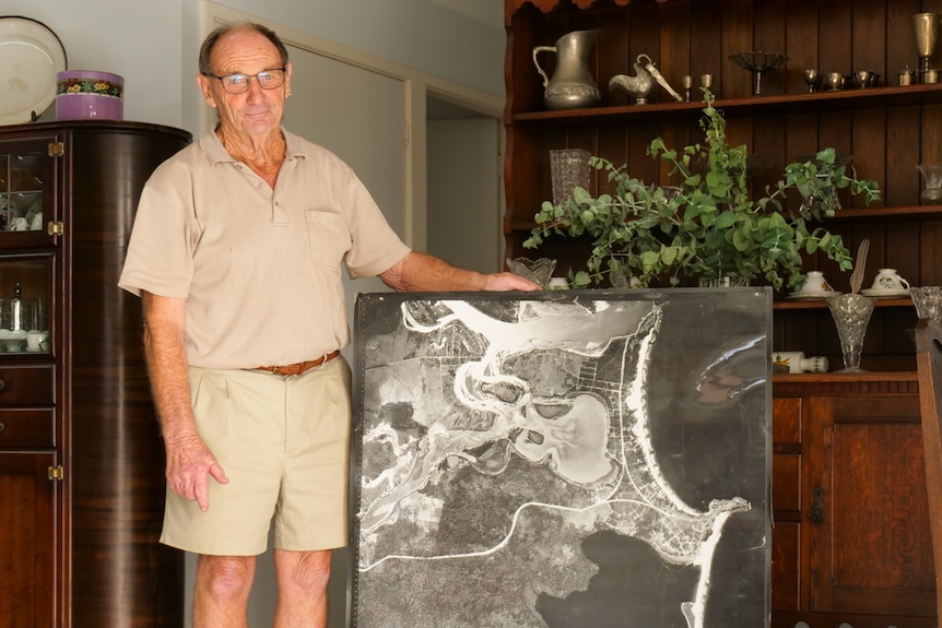A man stands with a large aerial photograph of Orient Point taken 60 years ago.