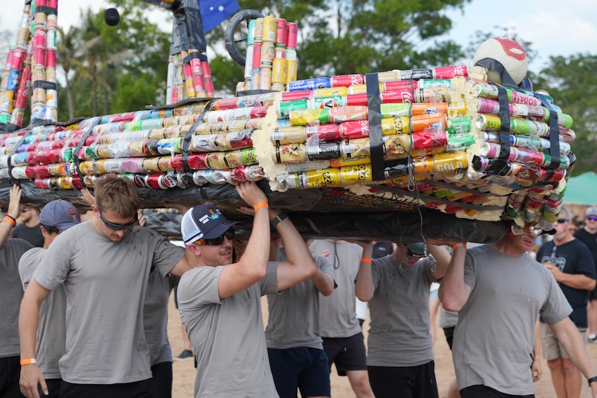 A group of men carrying a boat made of beer cans