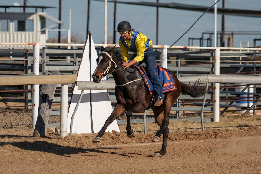 A female jockey rides a horse on a desert track 