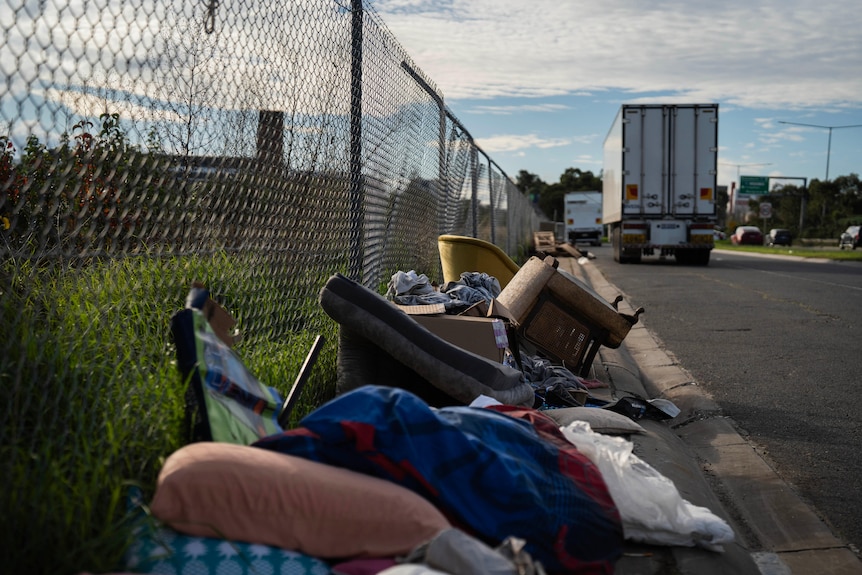 Rubbish piled up along a fence in a truck parking bay