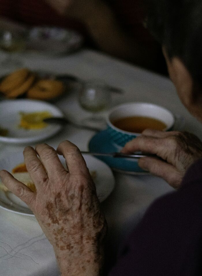 Close-up of elderly hands eating tea and biscuits, dementia care context