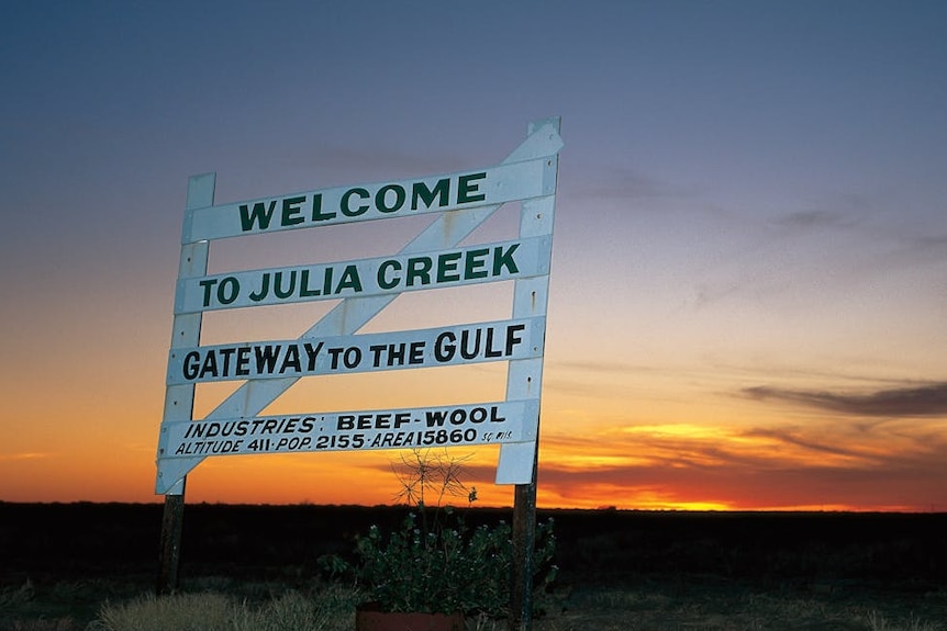 a sign that says 'julia creek gateway to the gulf' as the sun sets