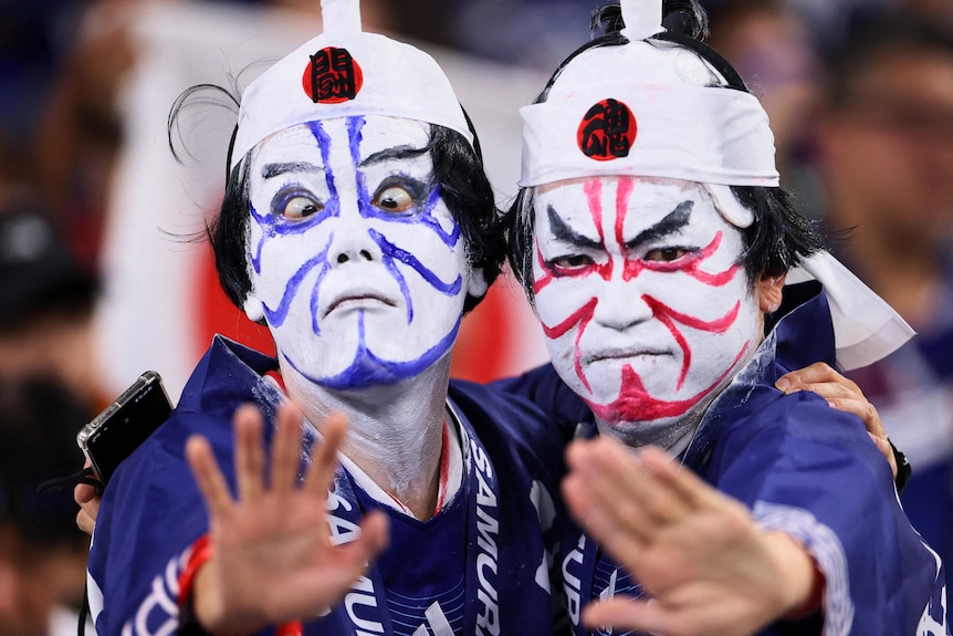 two people wearing traditional japanese dress and warrior face paint posing for the photo