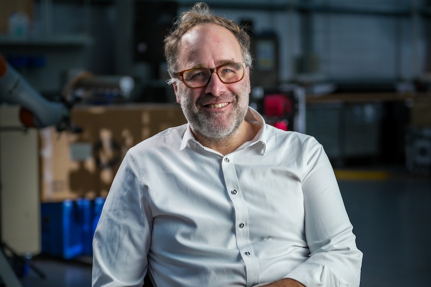 A man wearing glasses, smiling.