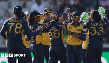 Sri Lanka's players, wearing dark blue and yellow shirts and blue trousers, exchange high fives to celebrate a wicket
