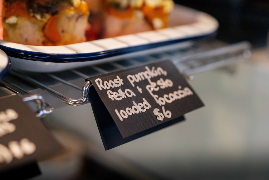 Food with a sign that says "roast pumpkin, feta, pesto focaccia $6"
